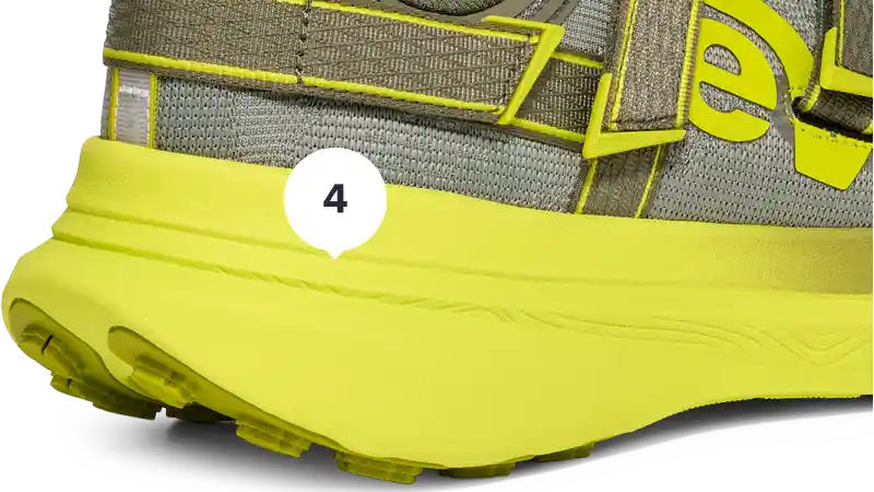Close-up of a shoe with a bright yellow sole and gray mesh upper.