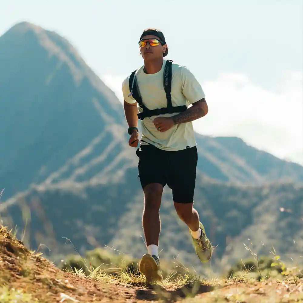Man running on a mountain trail with mountains in the background